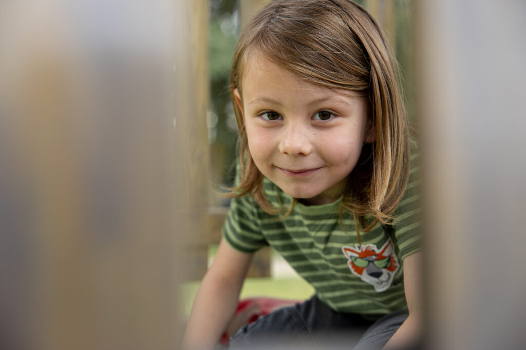 Kitakind schaut durch Holzbretter durch