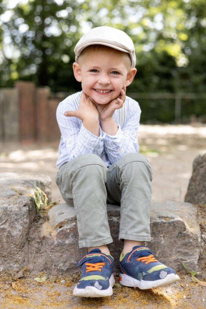 Kitajunge sitzt auf einem Stein und hat den Kopf in die Hänge gestützt