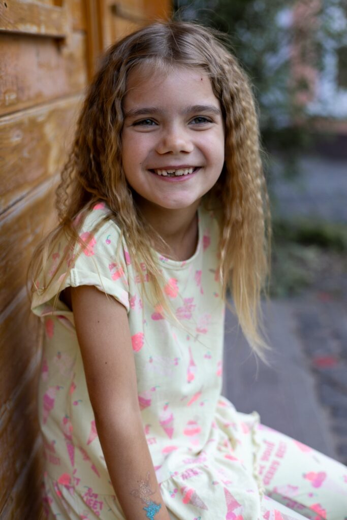 Kitamädchen sitzt an Holzhaus auf einer Bank