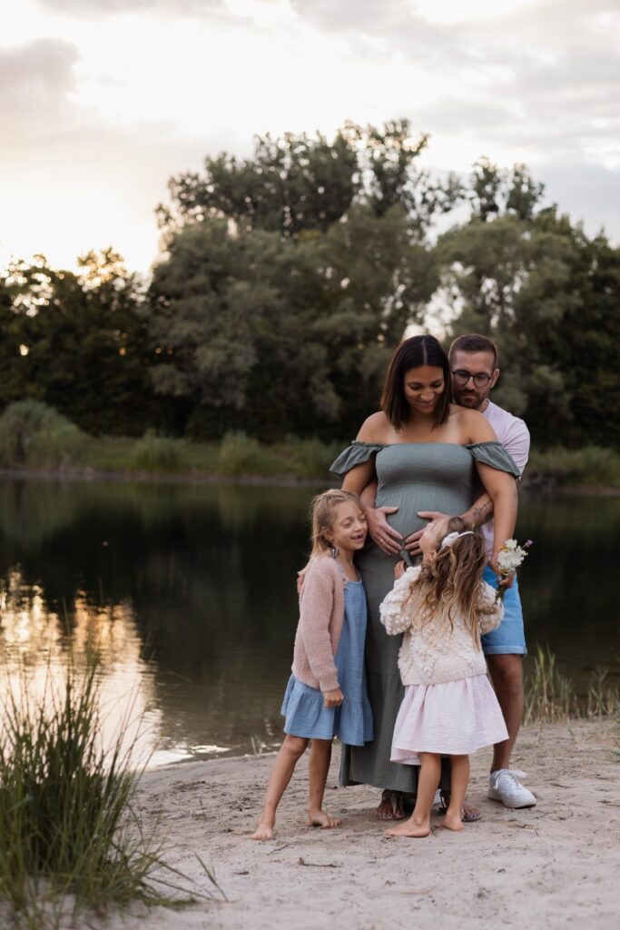 Familie steht am Wasser, Mama ist schwanger