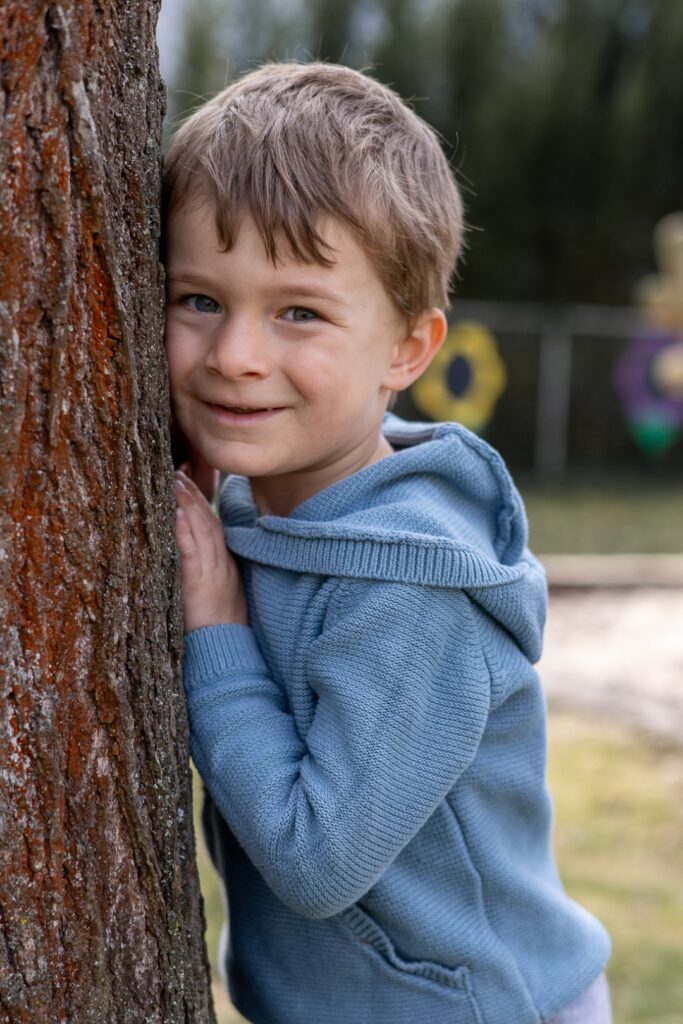 Kitakind lehnt mit dem Gesicht am Baum