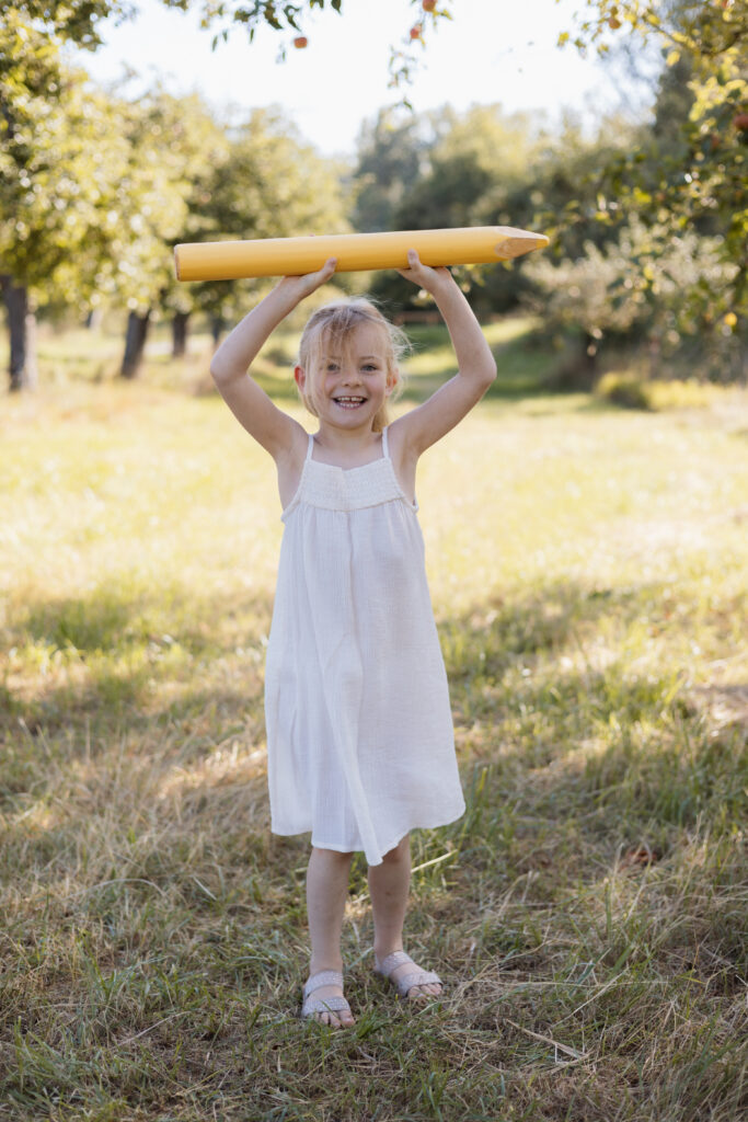 Schulkind hält übergroßen Stift über den Kopf