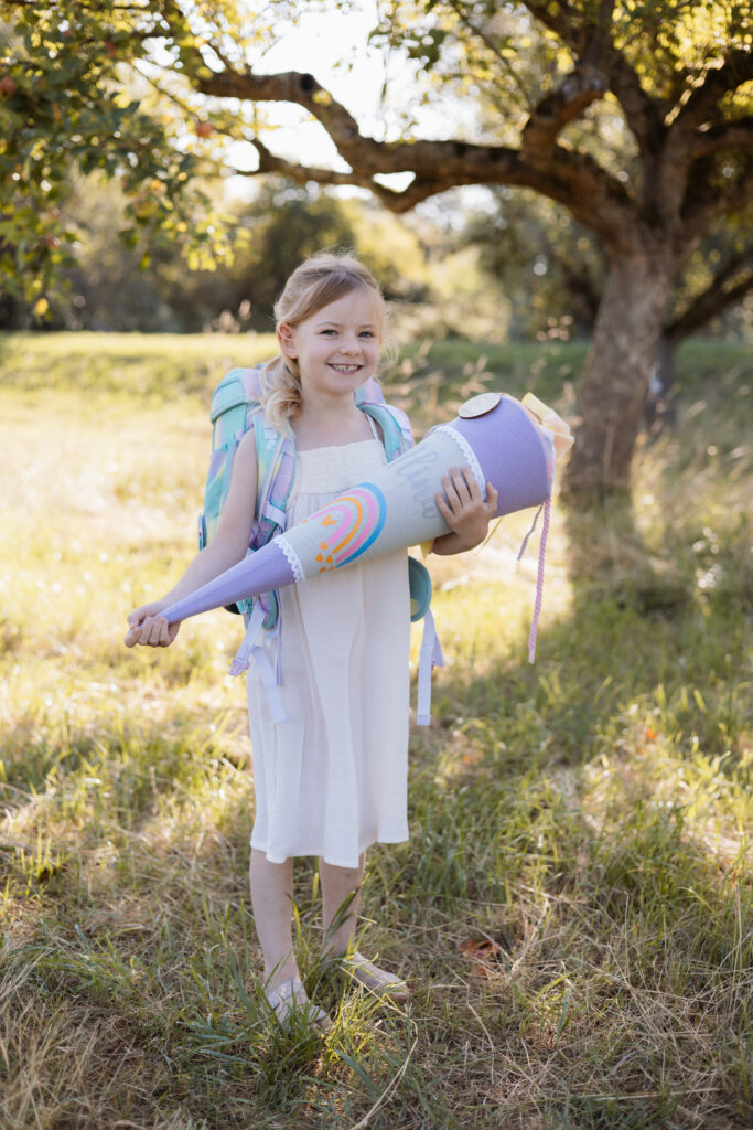 Schulkind hält Schultüte in der Hand und hat den Ranzen auf