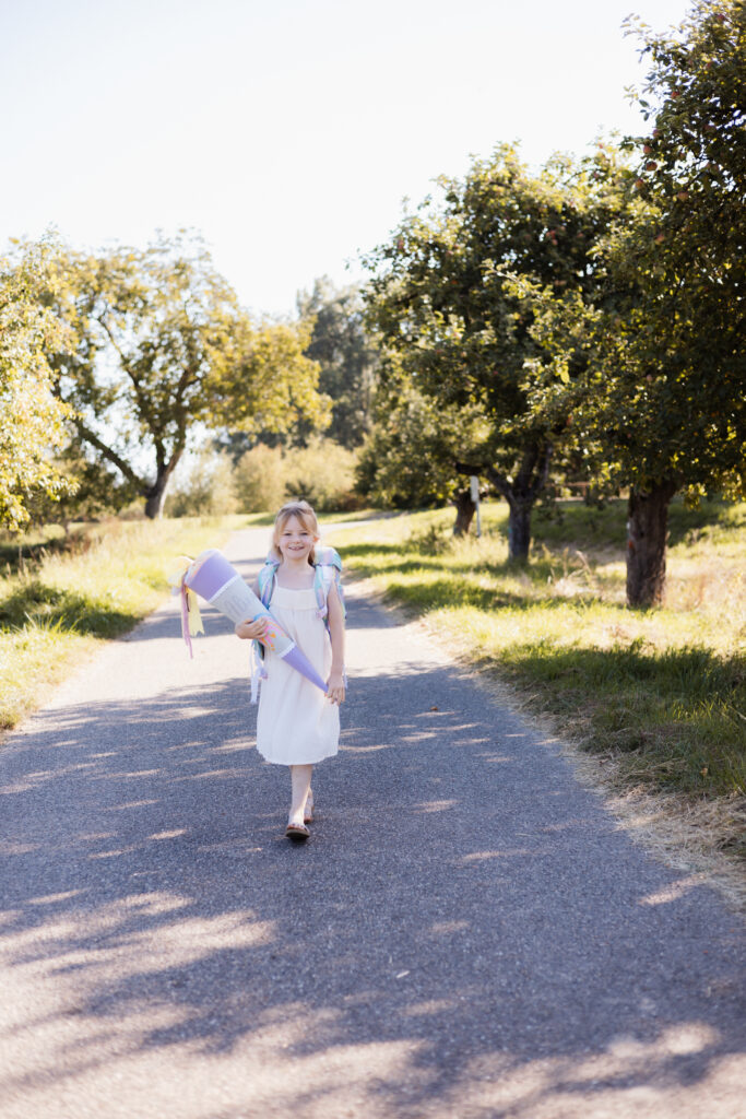 Schulmädchen mit Schultüte in der Hand läuft am Waldweg