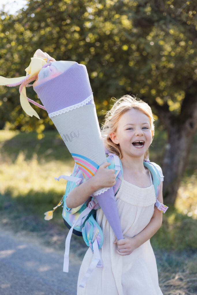 Schulmädchen mit Schultüte in der Hand und rennt freudig