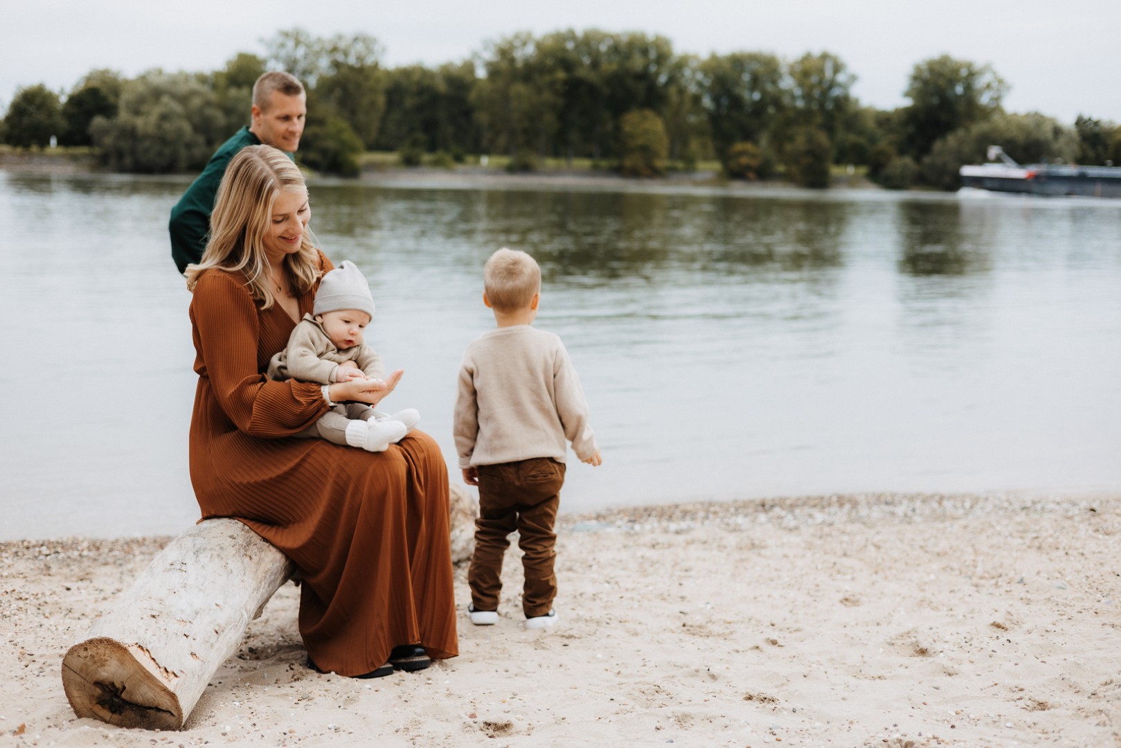 Familie sitzt am Strand auf einem Baumstamm