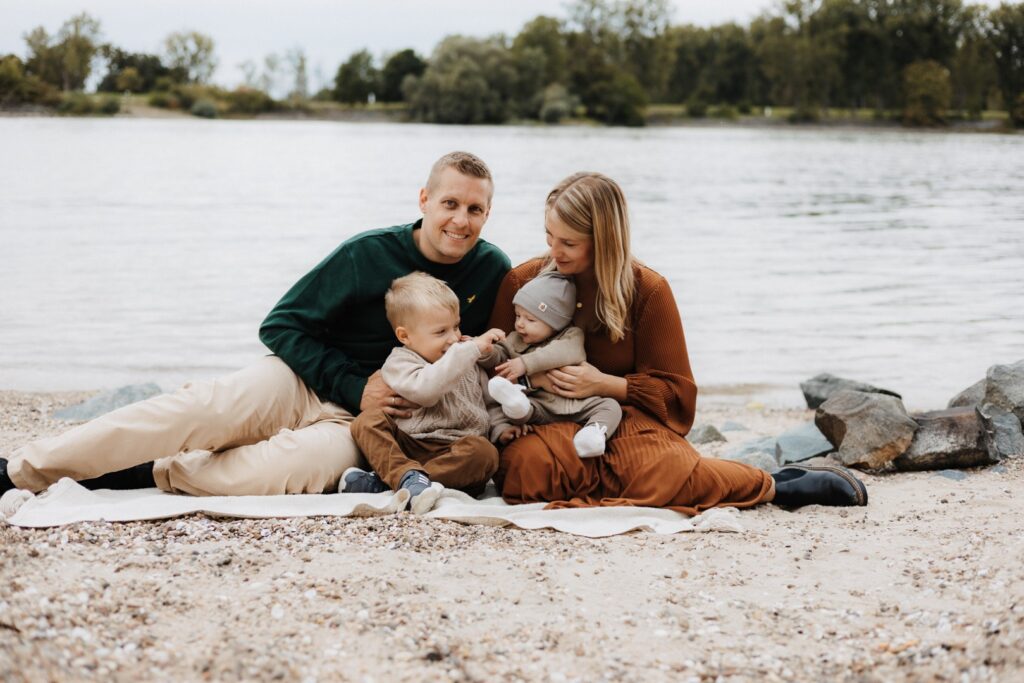 Familie mit 2 Jungs sitzt gemütlich am Strand
