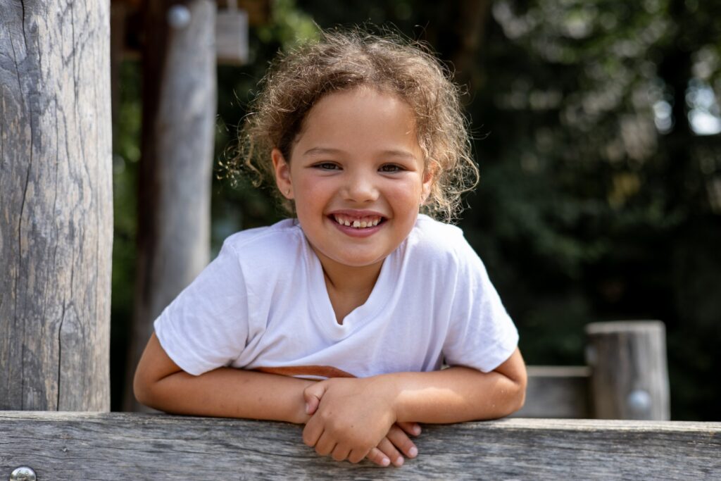 Kitakind auf dem Klettergerüst schaut lächelnd in die Kamera