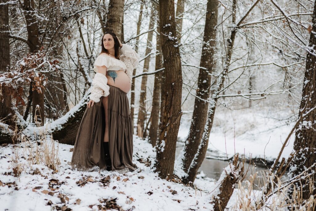Schwangere Frau steht im Wald mit Schnee