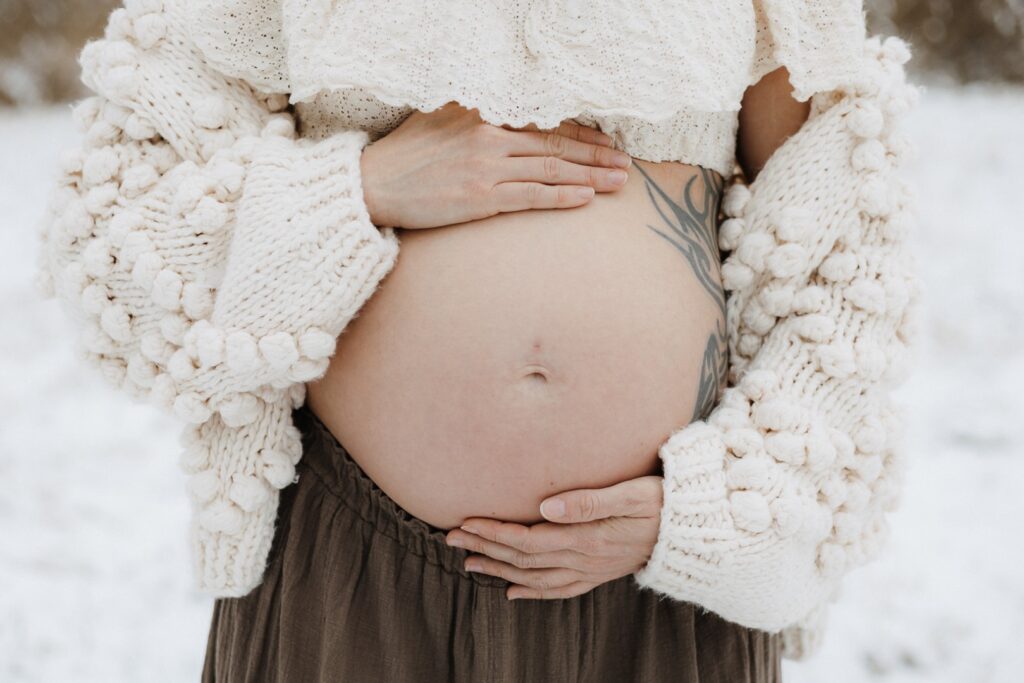 Detailbild vom nackten Babybauch im Schnee