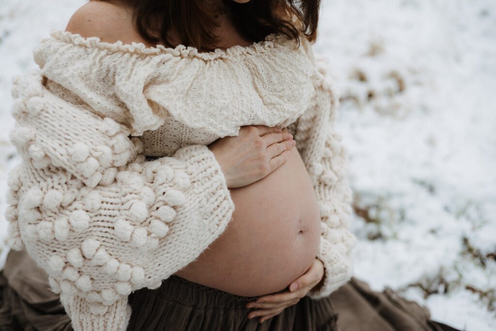 Detailbild vom nackten Babybauch im Schnee