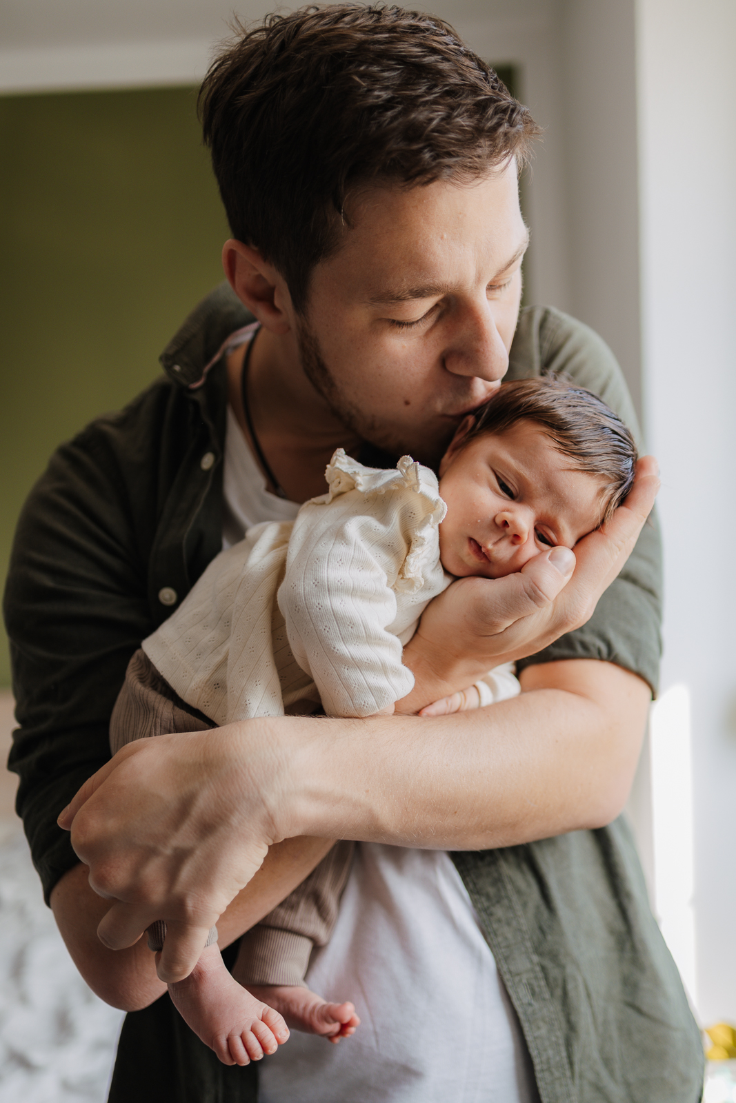 Papa hält sein Baby auf dem Arm und küsst den Kopf