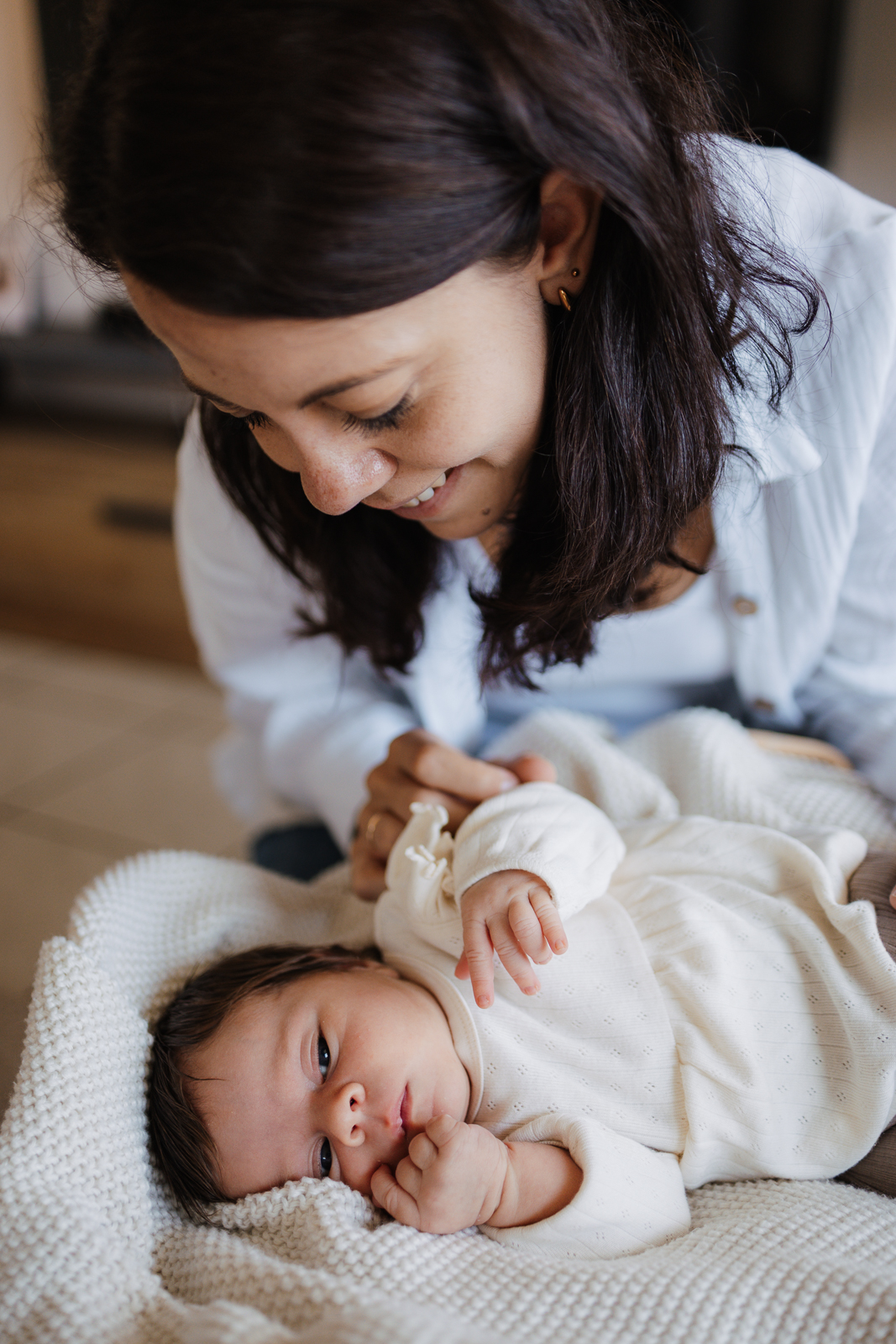 Baby liegt im Körbchen, Mama schaut ihr Baby an