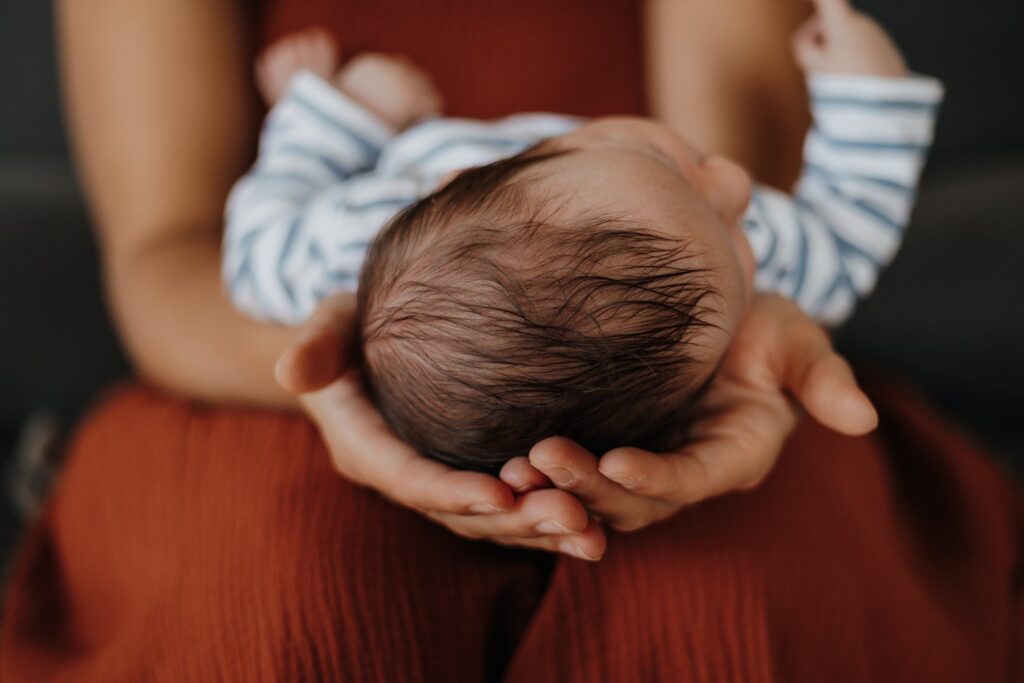 Mama hält ihr Baby - Detailfoto vom Kopf und Mamas Händen