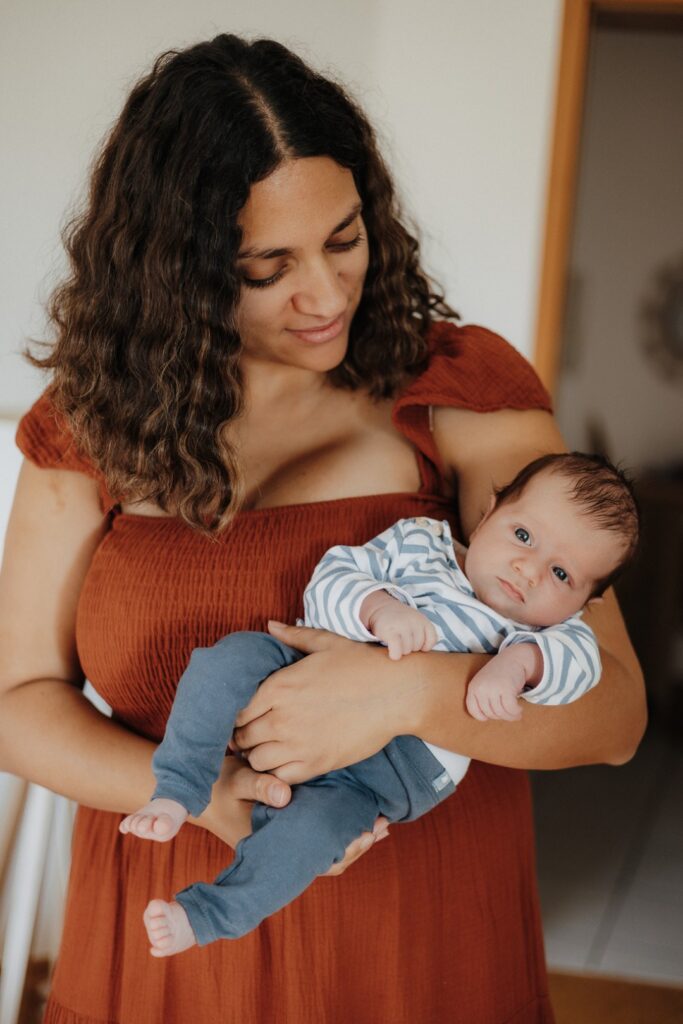 Mama hält ihr Baby auf dem Arm und schaut es an