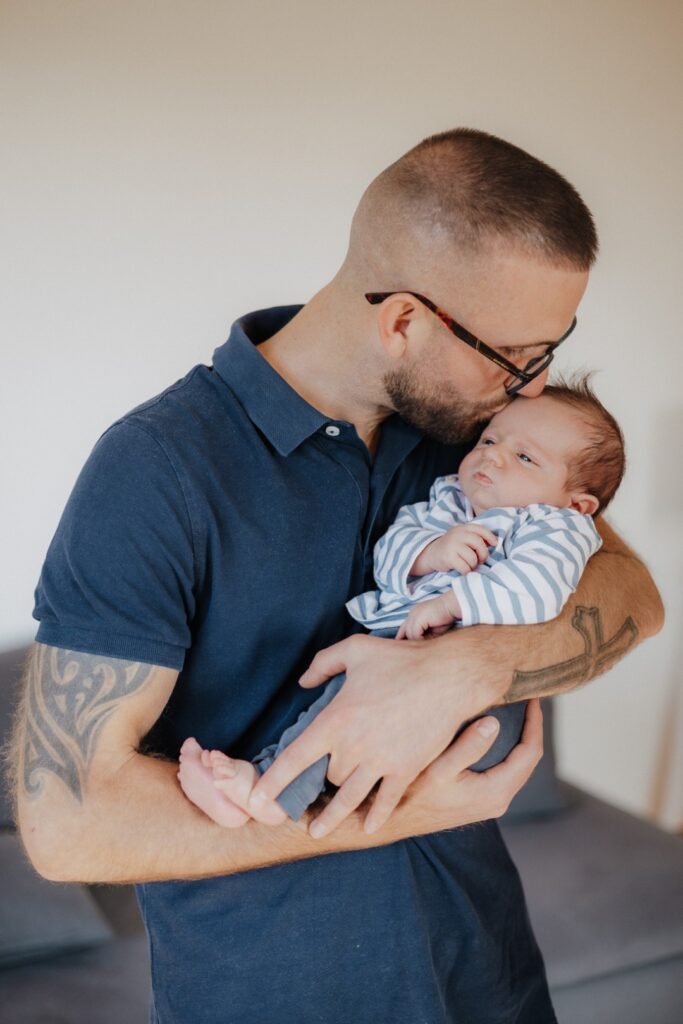 Papa hält sein Baby auf dem Arm und gibt einen Kuss auf den Kopf