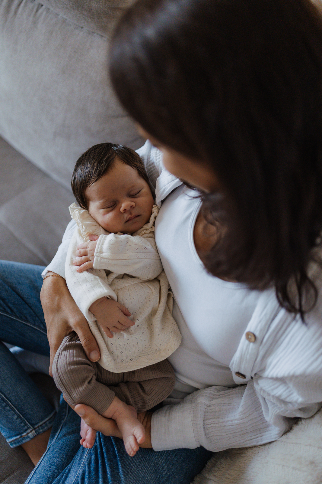 Mama hält ihr Baby im Arm und schaut es an.